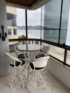 a table and chairs on a balcony with a view of the water at Cobertura frente ao mar Meia Praia -Itapema -SC in Itapema