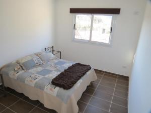 Cama en habitación blanca con ventana en Cabaña La Verdicchio Urbanización Cristobal Lote 2 en Valle Grande