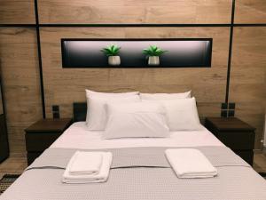 a bedroom with a large bed with two plants on the wall at Luxury Townhouse Suite in Larisa