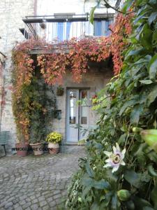 un edificio de piedra con una puerta y flores en la Casa sull'arco - Albergo diffuso Collelungo, en Collelungo