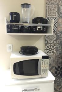 a white microwave oven sitting on top of a shelf at Apartamento Central -Centro Cunha in Cunha