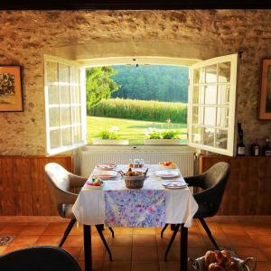 ein Esszimmer mit einem Tisch und einem Fenster in der Unterkunft Sans Souci Bed and Breakfast Luxe Heated Pool and Restaurant in Luzillé