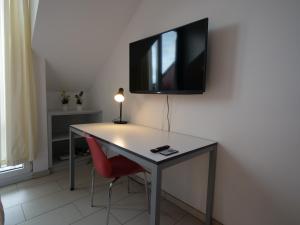 a desk with a television on a wall with a red chair at Rooftop Apartment by Rabe - Parkplatz & free Netflix & Balkon in Karlsruhe