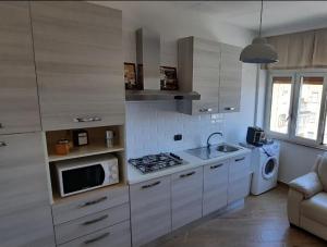 a kitchen with white cabinets and a sink and a microwave at Casatua in Taranto