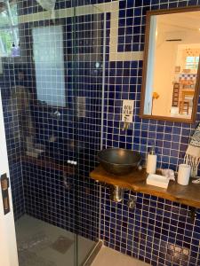 W wyłożonej niebieskimi kafelkami łazience znajduje się umywalka i miska. w obiekcie Loft do Alto-Araras w mieście Petrópolis