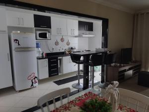 cocina con nevera blanca, mesa y sillas en Apartamento na Praia Grande en Praia Grande