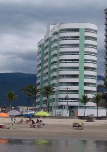 un edificio en la playa con gente sentada en la playa en Apartamento na Praia Grande en Praia Grande
