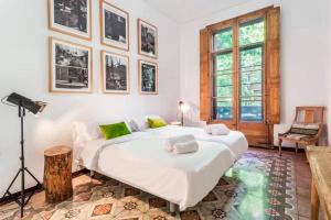 una camera da letto con un grande letto bianco con cuscini verdi di Factory Suites Barcelona a Barcellona