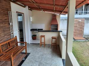 a patio with a bench and a kitchen with a stove at Casa de praia para temporada - Guriri in São Mateus