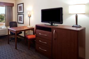 a hotel room with a television on a dresser with a desk at AmericInn by Wyndham Grimes in Grimes