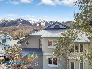 a house with a blue roof with mountains in the background at Aspect 2A in Thredbo