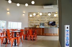 un restaurant avec des chaises orange, une table et un comptoir dans l'établissement Hotel Bait, à General Roca