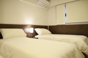 duas camas num quarto de hotel com lençóis brancos em Hotel Bait em General Roca