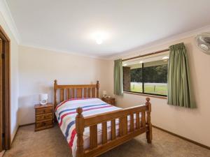 a bedroom with a wooden bed and a window at Armorel at Iluka in Iluka