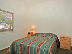 a bedroom with a bed and a lamp and a window at Bayview at Iluka in Iluka