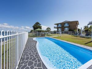 ein Schwimmbad mit einem Zaun und einem Haus in der Unterkunft Camawood 11 Iluka NSW in Iluka