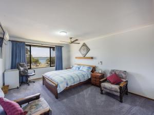 ein Schlafzimmer mit einem Bett, einem Stuhl und einem Fenster in der Unterkunft Camawood 11 Iluka NSW in Iluka
