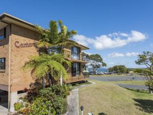 a building with a palm tree next to a street at Camawood 11 Iluka NSW in Iluka