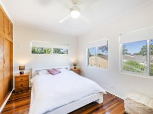 a bedroom with a white bed and two windows at Greenwood House in Iluka