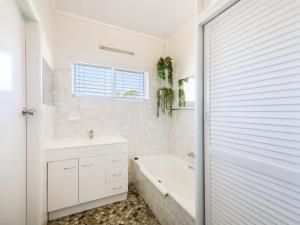 
a bathroom with a tub, sink and window at Greenwood House in Iluka
