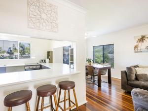 a kitchen and living room with a bar and stools at Greenwood House in Iluka