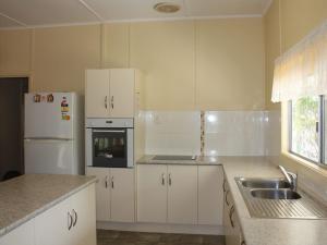 a kitchen with white cabinets and a sink and a refrigerator at Luka Land in Iluka