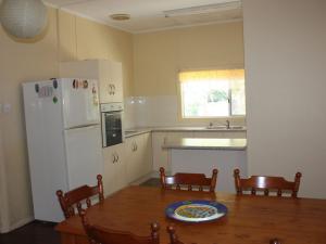 a kitchen with a table and a white refrigerator at Luka Land in Iluka
