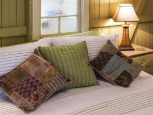 a bed with four pillows and a table with a lamp at little beach house in Iluka