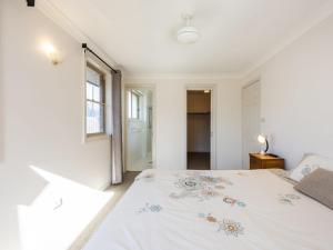 1 dormitorio con 1 cama con colcha blanca en Montrose by the Bay, en Iluka