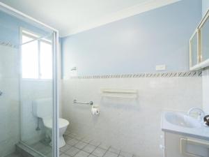 La salle de bains blanche est pourvue de toilettes et d'un lavabo. dans l'établissement Rainforest Retreat, à Iluka