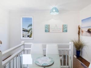 a dining room with a glass table and two white chairs at Sandy Feet in Iluka