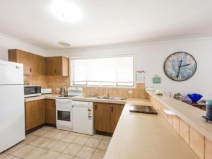 a kitchen with white appliances and a clock on the wall at Ripples on the Bay in Iluka