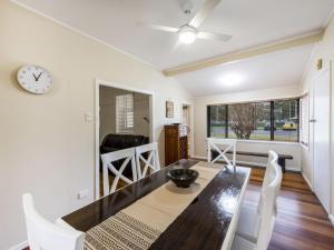 a dining room with a table and chairs and a clock at Salt Water Cottage in Iluka