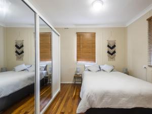 a bedroom with two beds and a mirror at Salt Water Cottage in Iluka