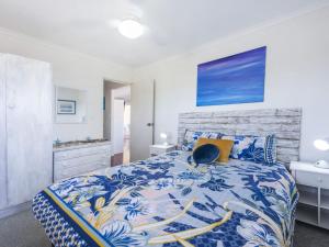 a bedroom with a bed with a blue and white bedspread at Sandy Feet in Iluka