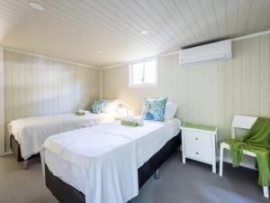 a room with two beds and a chair in it at The Net Shed in Iluka