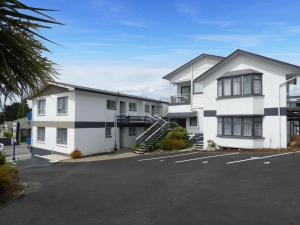 a parking lot in front of a white building at Anchor Motel in Timaru