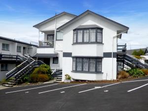 a white house with a parking lot in front of it at Anchor Motel in Timaru