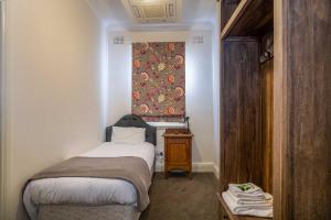 a small bedroom with a small bed and a window at Metropolitan Hotel in Orange