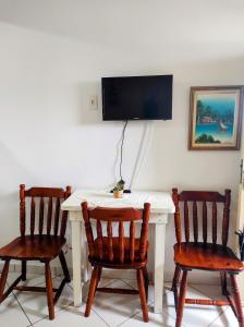a table with two chairs and a tv on a wall at Apto frente ao mar in Peruíbe