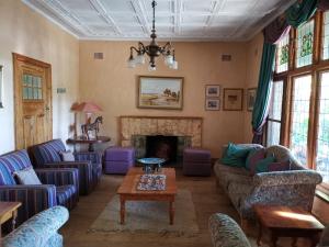 a living room with couches and a fireplace at Drakensberg Bush Lodge and Backpackers in Winterton