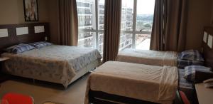 a hotel room with two beds and a large window at Flat Particular Jade Brasilia 1004 e 1006 Com Garagem in Brasilia +31 photos