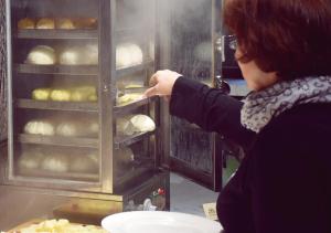 a woman in a kitchen looking at a loaf of bread at WO Hotel in Kaohsiung