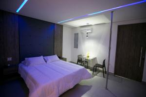 Un dormitorio con una gran cama blanca y una mesa en Hauss Excellence Motel, en Sete Lagoas