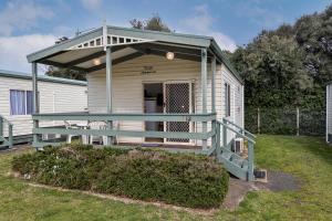 Una pequeña casa con porche y terraza. en Narrawong Island Holiday Park, en Narrawong