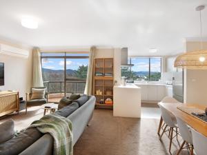 a kitchen and living room with a couch and a table at Avalanche 6 Stylish Modern Apartment in Central Location in Jindabyne