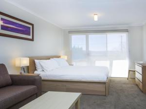 a bedroom with a bed and a couch and a window at Cascades 3 - Studio Apartment l Free WiFi l Central Location l Bath in Jindabyne