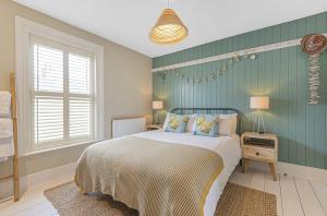 a bedroom with a bed and a green wall at Seagrass Cottage in Southwold, Stunning Property with Views! in Southwold