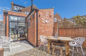 an outdoor patio with a wooden table and chairs at Seagrass Cottage in Southwold, Stunning Property with Views! in Southwold