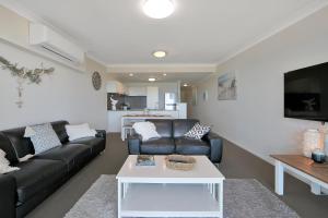 a living room with a black couch and a table at The Point Resort in Bargara